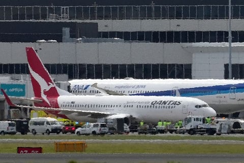 A Qantas Boeing 737-800 aircraft operating as flight QF144 is seen past heat haze after its safe landing at the Sydney International Airport on January 18, 2023. - Ambulance services scrambled at Sydney airport on January 18 to meet an incoming Qantas plane that issued a mid-air mayday alert with engine trouble before landing safely. (Photo by Andrew LEESON / AFP)