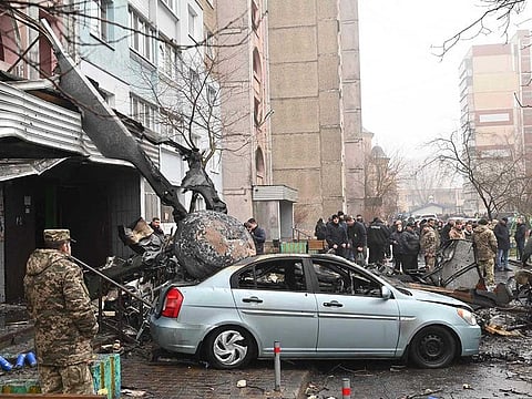 Military and onlookers stand at the site where a helicopter crashed near a kindergarten outside the capital Kyiv, killing 16 people, including two children and Ukrainian interior minister, on January 18, 2023.