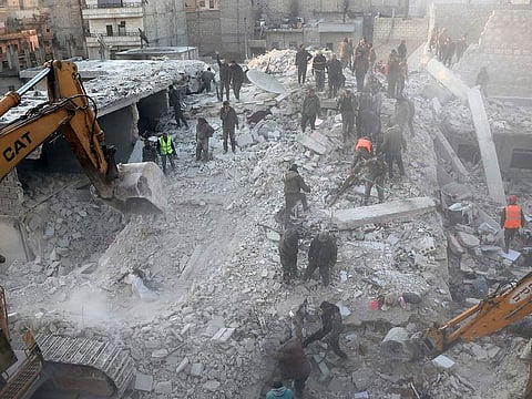 In this photo provided by Kurdish-run Hawar News Agency, civil defense workers and civilians work on the rubble of a destroyed building in the Sheikh Maksoud neighborhood in Aleppo, Syria, Sunday, Jan. 22, 2023. 