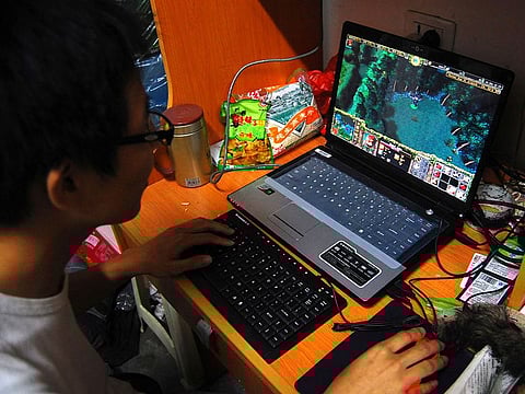 A college student plays the online game World of Warcraft in his dormitory room in southwest China's Chongqing city on Oct. 12, 2009.