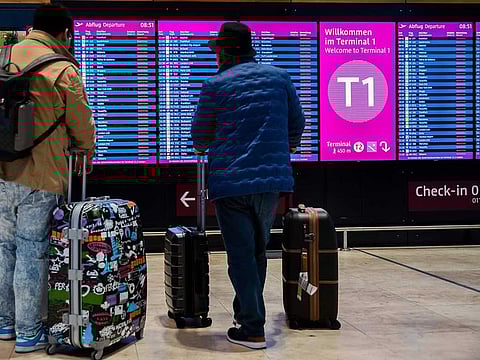 Passengers look at a display board showing all flights as cancelled during a warning strike at Berlin-Brandenburg BER Airport in Schoenefeld, Germany, Wednesday, Jan. 25, 2023. All flights were cancelled Wednesday at Berlin’s airport after ground staff went on strike to press their demands for higher pay.  