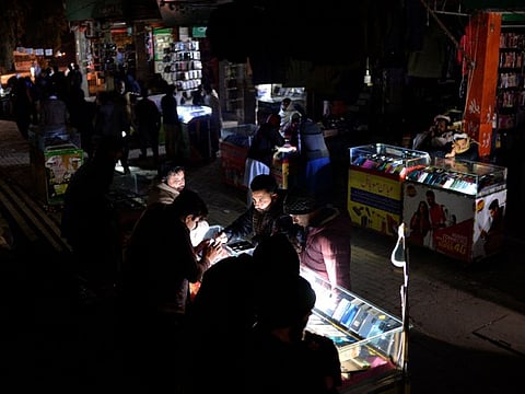 Shopkeepers sit at a market during a nationwide power outage in Islamabad on January 23, 2023.  