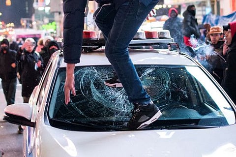 A protestor steps on the windshield of a police vehicle, on the day of the release of a video showing police officers beating Tyre Nichols, the young Black man who died three days after he was pulled over while driving during a traffic stop by Memphis police officers, in New York, on January 27, 2023.  