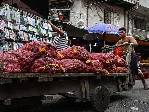 A worker pushing a cart of onions at a market in Manila.