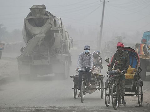 Commuters make their way along a street amid dusty conditions in Dhaka on January 25, 2023. 