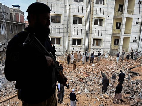 A policeman stands guard as labourers remove debris beside a damaged mosque following January's 30 suicide blast inside the police headquarters in Peshawar on February 1, 2023. 