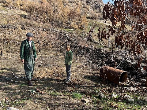 Omar Abdullah Qasim stands with his grandson in the yard next to his house in Sararo village, where he claims several rockets landed during the Turkish bombardment last year, in Dohuk, Iraq, December 27, 2022.  