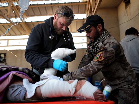This file picture taken on November 28, 2016 shows US volunteer and former US Marine Pete Reed giving the first aid to an injured Iraqi woman, at an outdoor field clinic in the Samah neighbourhood of Mosul.  