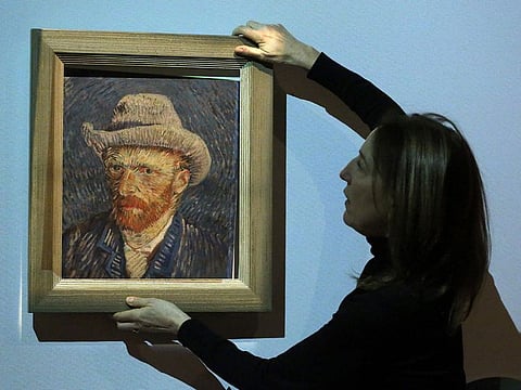 Emilie Gordenker, director of the Van Gogh Museum, removes the frame of a reproduction of the painting "Self-Portrait with Grey Felt Hat" by Vincent Van Gogh as part of an interactive section of the exhibition "Choosing Vincent - Portrait of a family history" at Van Gogh Museum in Amsterdam, on February 8, 2023. 