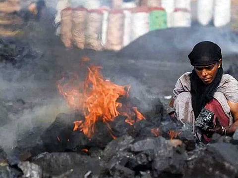 Coal scavenger Anita Devi burns coal before selling it for use at a depot in a mining area of Jharia coalfield, India, Nov 11, 2022. 