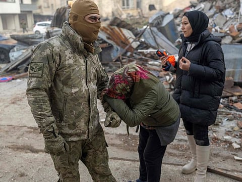A woman pleads to a Turkish soldier to save her son, next to the rubble of a collapsed building in Hatay, southeastern Turkey, on February 8, 2023.