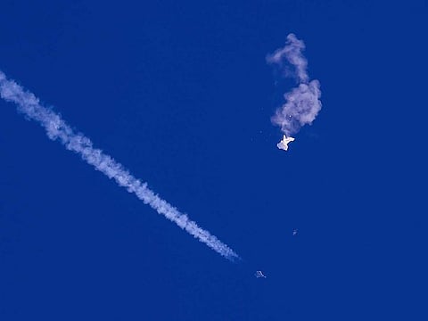 In this photo provided by Chad Fish, the remnants of a large balloon drift above the Atlantic Ocean, just off the coast of South Carolina, with a fighter jet and its contrail seen below it, Feb. 4, 2023.  