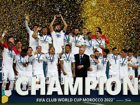 Real Madrid's Karim Benzema lifts the trophy with teammates and coach Carlo Ancelotti after winning the FIFA Club World Cup final.