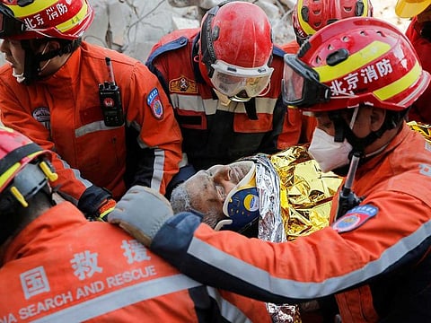 Turkish and Chinese rescuers carry Malek, a 55-year-old Syrian refugee man, into an ambulance after he was rescued from the wreckage of a destroyed building in the aftermath of the deadly earthquake in Hatay, Turkey February 12, 2023. 