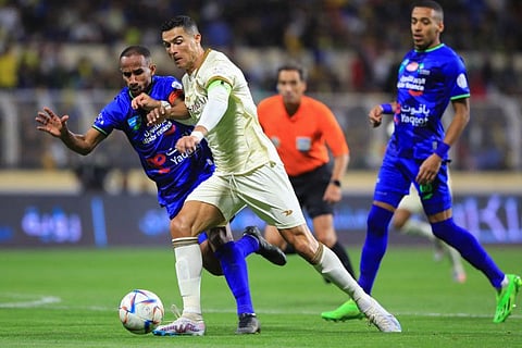 Al Nassr's Portuguese forward Cristiano Ronaldo (right) dribbles past Al Fateh's Saudi midfielder Mohammed Al Fuhaid (left) during the Saudi Pro League  match at the Prince Abdullah bin Jalawi Stadium in Al Hasa. Al Nassr won 4-0 with Ronaldo scoring all four goals.