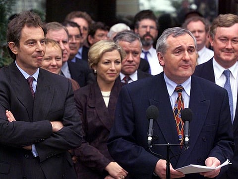 File: British Prime Minister Tony Blair listens as Ireland's Taoiseach Bertie Ahern addresses the media on the outcome of the Northern Ireland peace process talks outside Castle Buildings, announcing that the two governments want the formation of a power-sharing Executive (April 1998)