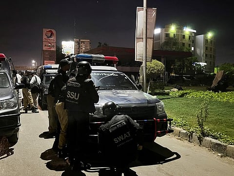 Police take position after a police HQ building was attacked by gunmen in Karachi on February 17, 2023. 