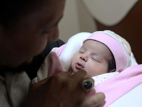Khalil Al Sawadi looks at Afraa, a baby girl who was born under the rubble caused by an earthquake that hit Syria and Turkey, in the town of Jinderis, Aleppo province.