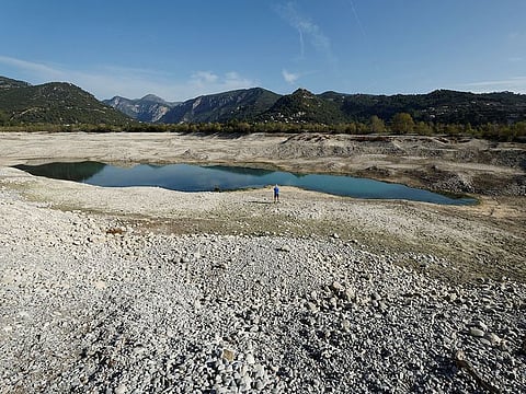 FILE PHOTO: A man stands on the dried-up artificial Broc lake in Le Broc near Nice as the Alpes-Maritimes department faces a severe drought, France, October 28, 2022.