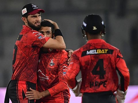Lahore Qalandars' captain Shaheen Shah Afridi (left) celebrates with teammate Sikandar Raza (centre) after the dismissal of Quetta Gladiators' Mohammad Nawaz (not pictured) during the Pakistan Super League (PSL) T20 cricket match at the National Stadium in Karachi.