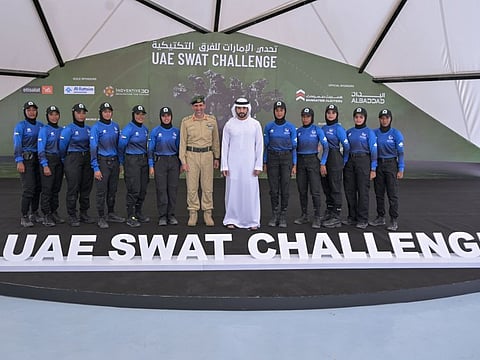 Sheikh Hamadan bin Mohammed and Lieutenant General Abdullah Khalifa Al Marri standing for photo with the Dubai Police all women Swat team