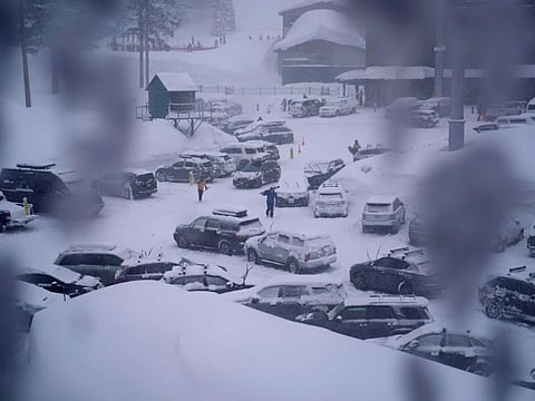 People through the parking area of the Alpine Base Area at Palisades Tahoe during a winter storm on February 24, 2023, in Alpine Meadows, California.