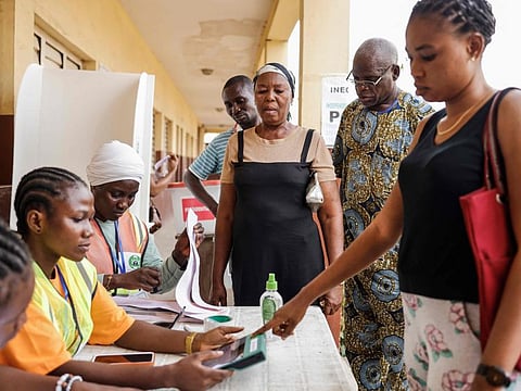 A voter looks on as another gets her information checked in the Bimodal Voter Accreditation System (BVAS) by an Independent National Electoral Commission (INEC) official at a polling station in Agege, Lagos, on February 25, 2023, during Nigeria's presidential and general election.  