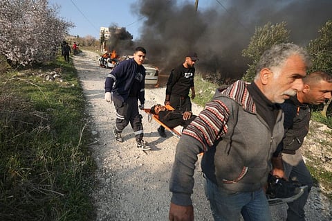 Palestinians carry a youth injured during clashes with Israeli settlers from the nearby Bracha settlement, who reportedly set fire to cars in Burin village in the West Bank on February 25, 2023. 