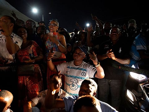 People follow the ballot counting, lit-up by car headlights, at a polling station, after polls were closed on election day in Lekki, Lagos, Nigeria.