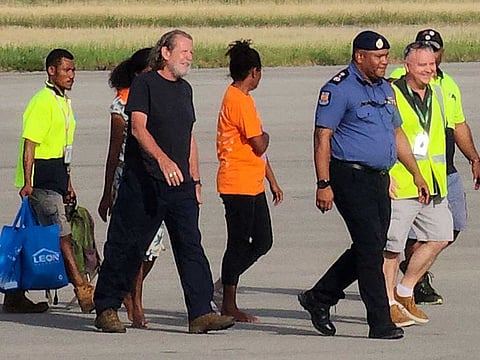 Bryce Barker (3rd L), who was held for a week in the Papua New Guinea highlands by an armed group, is escorted from a plane following his release in Port Moresby on February 26, 2023. 