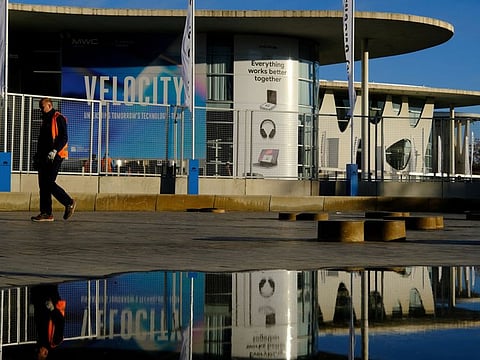 Workers walk past billboards of GSMA's 2023 ahead of the Mobile World Congress (MWC) in Barcelona, Spain.