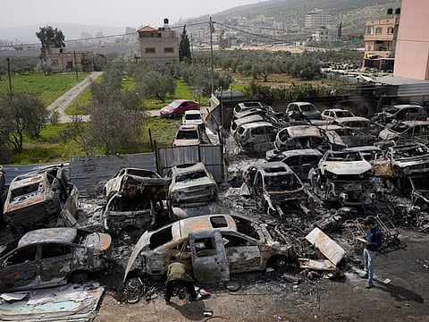 Palestinians inspect scorched cars in a scrapyard, in the town of Huwara, near the West Bank city of Nablus, on Monday.