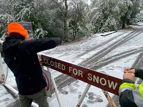 A parks worker puts up a closed sign at the entrance to Mount Tamalpais State Park in Mill Valley, Calif., Friday Feb. 24, 2023.