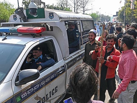 Supporters of former Pakistan's prime minister Imran Khan gather around a police van outside his house in Lahore on March 5, 2023.