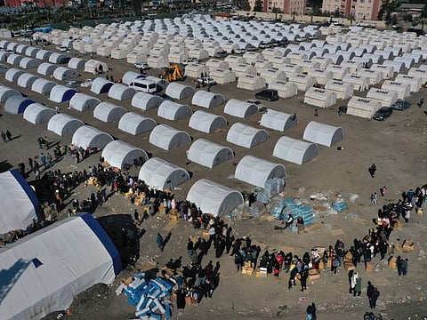People who lost their houses in the devastating earthquake, lineup to receive aid supplies at a makeshift camp, in Iskenderun city, southern Turkey, Tuesday, Feb. 14, 2023.