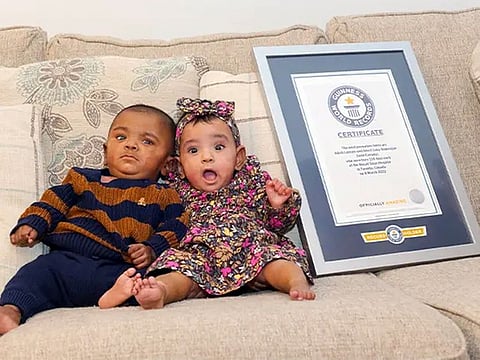 A photo of the twins sitting on a couch next to their GWR framed certificate shows Adiah looking surprised with her mouth wide open, while her brother Adrial appears pensive.