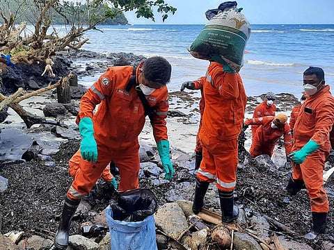 Coast guard personnel and volunteers collecting debris covered with oil during a clean-up along the coast in Pola, Oriental Mindoro Province, days after an oil spill from a sunken tanker. 