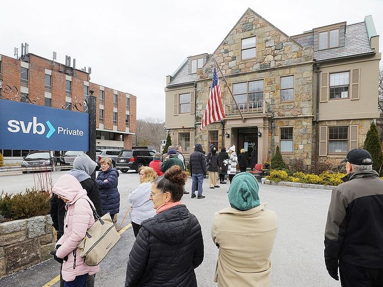 Customers wait in line outside a branch of the Silicon Valley Bank (SVB)