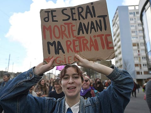 A protester holds a placard reading "I will be dead before I retire" during a demonstration a day after the French government pushed a pensions reform through parliament without a vote, using the article 49.3 of the constitution, in Rennes, western France, on March 17, 2023. 