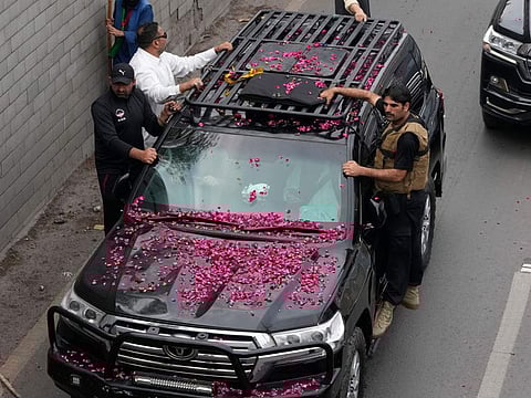 Security personnel climb on a vehicle carrying former Prime Minister Imran Khan as it moves toward Islamabad at a road in Lahore, on March 18, 2023.  