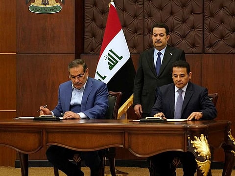 Iraqi Prime Minister Mohammed Shia Al Sudani looks on as Iraq's National Security Adviser Qasim Al Araji and Iran's Supreme National Security Council secretary Ali Shamkhani sign the security agreement that includes coordination in protecting the common borders between the two countries, in Baghdad, Iraq, March 19, 2023. 