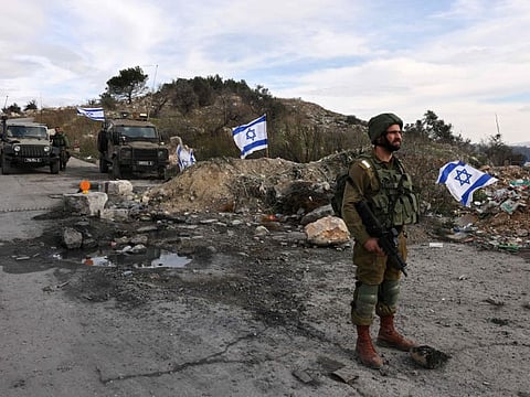 In this file photo taken on December 30, 2021 Israeli soldiers guard the road leading to the Homesh Yeshiva (religious school), located at the former colony of Homesh, west of the West Bank city of Nablus.  
