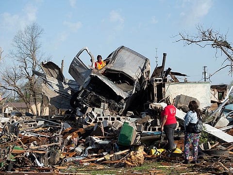 KeUntey Ousley tries to salvage what he can from his mother's boyfriend's vehicle, as his mother LaShata Ousley and his girlfriend Mikita Davis watch, after a tornado cut through their small Delta town the night before in Rolling Fork, Mississippi, U.S.