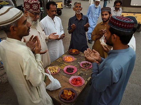 Devotees pray before ending their fast along a street during the month of Ramadan, in Karachi on March 26, 2023.