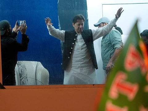 Protected by a bulletproof barrier, former Prime Minister Imran Khan waves to supporters during a rally in Lahore, Pakistan, Sunday, March 26, 2023, to pressure the government of Shahbaz Sharif to agree to hold snap elections.