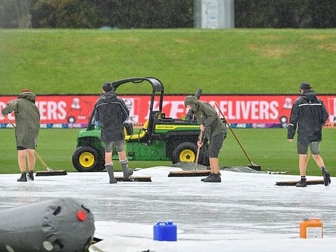 Ground staff sweep water off the covers as rain falls before the start of the second one-day international cricket match between New Zealand and Sri Lanka at Hagley Oval in Christchurch.