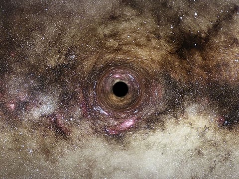 An artist’s impression of a black hole in the Milky Way galaxy, which distorts light passing near it creating a phenomenon known as “gravitational lensing”. - One of the largest black holes ever recorded has been discovered using a new technique that could spot thousands more of the celestial monsters in the coming years, according to astronomers.  