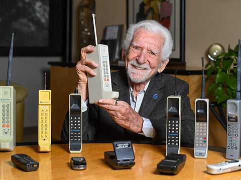 Engineer Martin Cooper holds a contemporary copy of the original cell phone he used to make the first cell phone call on April 3, 1973, in Del Mar, California on March 20, 2023. - The problem with mobile phones is that people look at them too much. At least, that's according to the man who invented them 50 years ago. Martin Cooper, an American engineer dubbed the "Father of the cell phone," says the neat little device we all have in our pockets has almost boundless potential and could one day even help conquer disease. But right now, we can be a little obssessed. (Photo by VALERIE MACON / AFP)