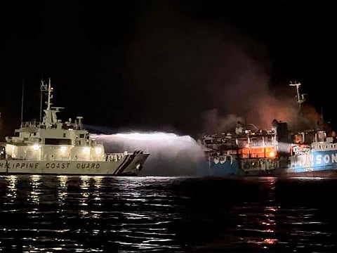 This handout picture taken on March 29, 2023 and released by the Philippine Coast Guard shows the Philippine Coast Guard spraying water on a fire onboard the Lady Mary Joy 3 during a search and rescue operation in waters off Baluk-Baluk Island in Basilan province. 