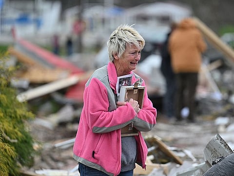 Debbie Lowdermilk holds photographs as she reacts while looking at the destroyed school she owns the day after a tornado hit Sullivan, Indiana, U.S. April 1, 2023